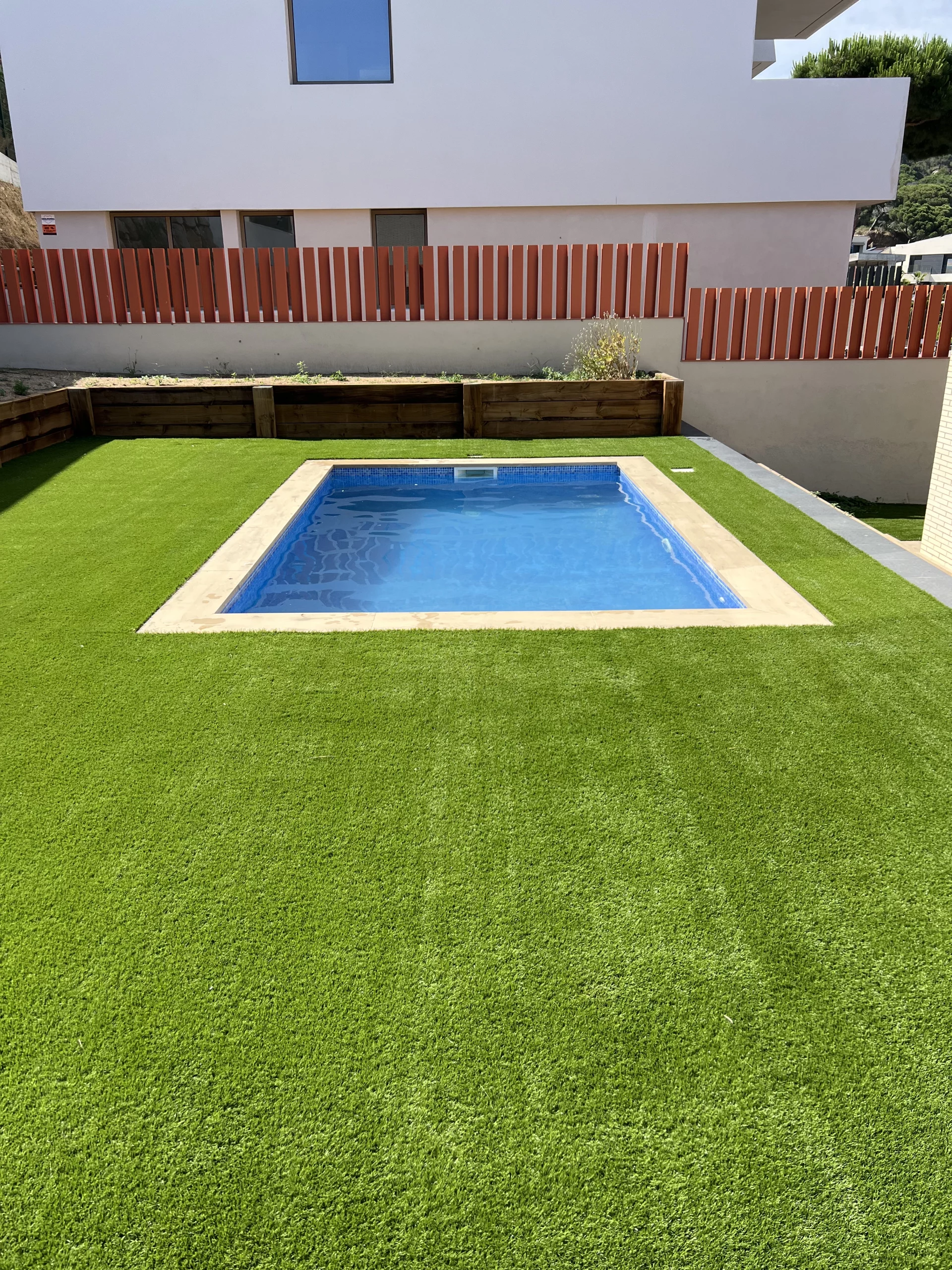 Piscina compacta amb revestiment blau i terrassa